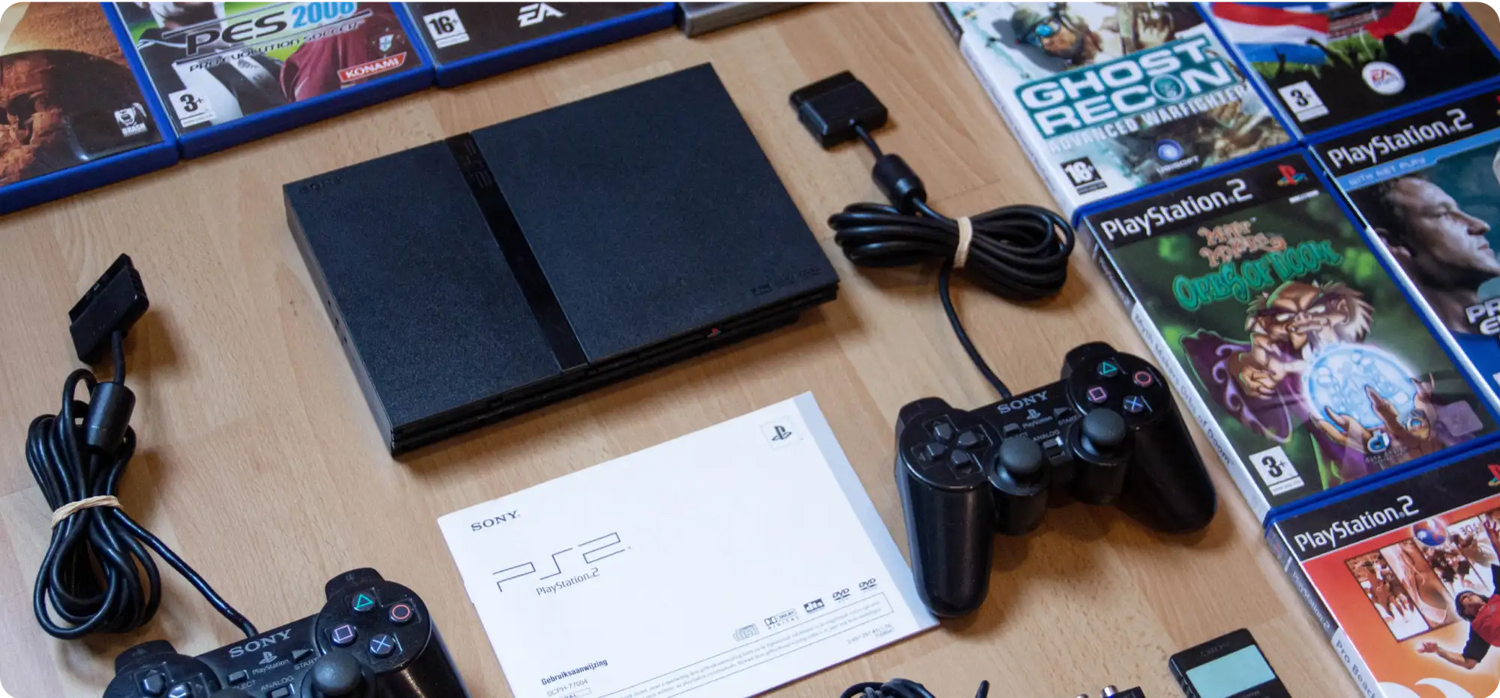 Schwarze PlayStation 2 Konsole mit Controllern und Spielen.